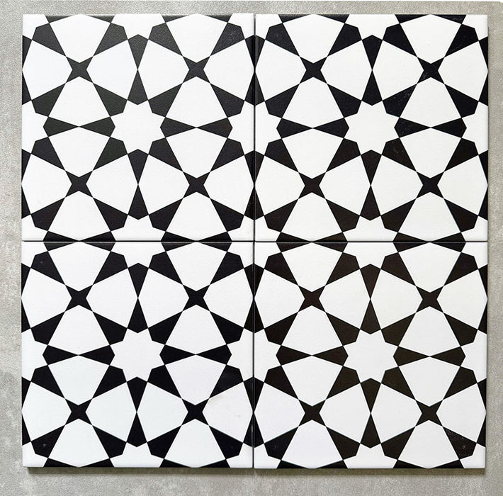 Agadir Schwarz & Weiß Fliesen im marokkanischen Stil im Format 20 × 20 cm aus Feinsteinzeug, als Vierer-Anordnung dargestellt, um das sich wiederholende geometrische Sternmuster in Schwarz und Weiß auf neutralem Hintergrund zu zeigen.