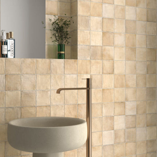 Badezimmerwand mit Zellige Sandbeige Matt Quadrat Keramikfliesen im marokkanischen Stil im Format 10 × 10 cm, in sanften Beige- und Sandtönen. Im klassischen Raster rund um ein freistehendes Waschbecken mit Messingarmatur verlegt, sorgen feine Farbnuancen und leicht unregelmäßige Kanten für ein authentisches, handgefertigtes Zellige-Effekt-Finish.