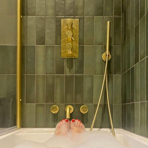 Badezimmer mit Zellige Malachitgrün Matt Keramik-Riemchenfliesen im marokkanischen Stil im Format 6,5 × 20 cm, rund um Badewanne und Dusche an den Wänden verlegt. In Kombination mit gebürsteten Messingarmaturen, einem Waschtisch aus Holz und einem Steinwaschbecken entsteht ein warmes, spa-ähnliches Ambiente.