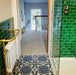 Badezimmer mit Berlin Stadt Bodenfliesen im Format 20 × 20 cm im viktorianisch-marokkanisch inspirierten Stil. Gestaltet mit glänzenden grünen Metro-Wandfliesen, einem Handtuchhalter aus Messing und einer Glasduschabtrennung für einen dekorativen, gemusterten Boden.