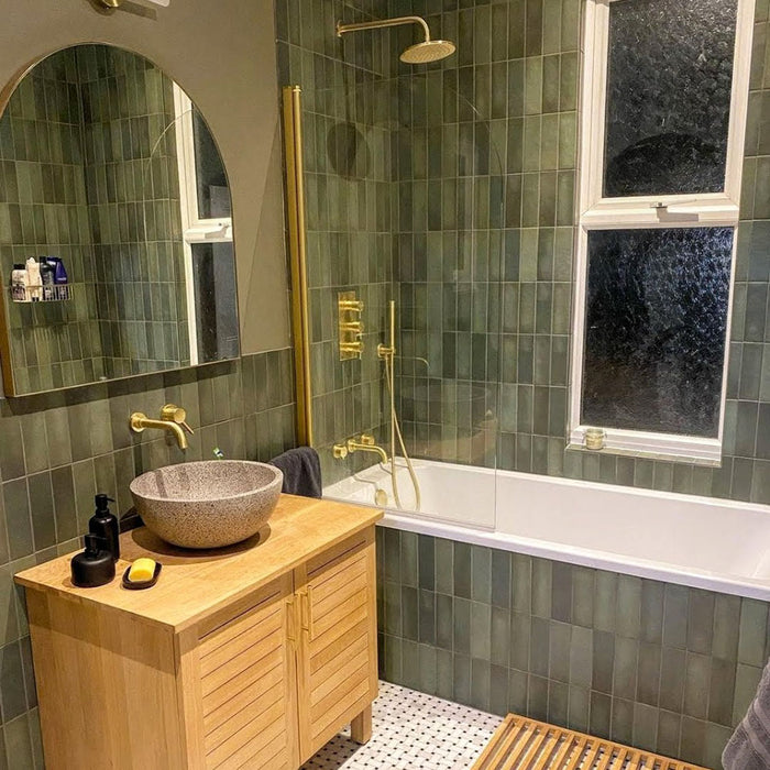 Badezimmer mit Zellige Malachitgrün Matt Keramik-Riemchenfliesen im marokkanischen Stil im Format 6,5 × 20 cm, rund um Badewanne und Dusche verlegt. Gebürstete Messingarmaturen, ein Holzwaschtisch und ein Steinwaschbecken unterstreichen den warmen, ruhigen Spa-Look.