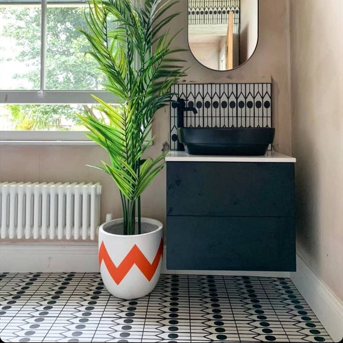 Badezimmer mit Almeira Felis Feinsteinzeugfliesen im marokkanischen Stil als Bodenbelag, Format 20 × 20 cm, mit einem geometrischen Punkt- und Linienmuster in Schwarz und Weiß. Kombiniert mit modernem Waschtisch und Zimmerpflanzen für ein frisches Ambiente.