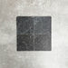 Vier Fayrouz Black Naturmarmorfliesen im Format 15,2 × 15,2 cm mit getrommelter Oberfläche, gemeinsam arrangiert. Sichtbar werden tiefe Anthrazittöne, natürliche Maserungen und feine Oberflächenvariationen vor einem neutralen, strukturierten Hintergrund.
