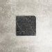 Single Fayrouz Black 15.2x15.2cm natural marble tile with a tumbled finish, featuring deep charcoal tones and striking natural veining, displayed against a neutral textured background in a clean product setting.