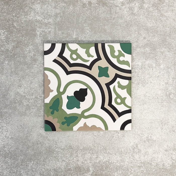 Einzelne Berlin Bindung Feinsteinzeugfliese im Format 20 × 20 cm im viktorianisch-marokkanisch inspirierten Stil in einer Produktszene. Gezeigt wird ein dekoratives geometrisches Muster in Grün-, Schwarz-, Beige- und Cremetönen, inspiriert von traditionellen Bodenfliesen im viktorianischen Stil.