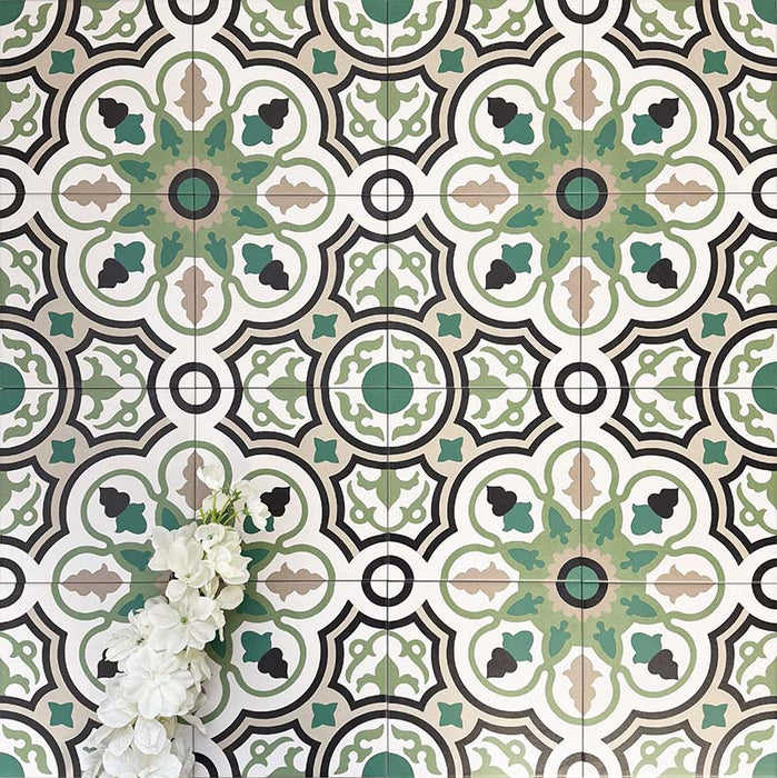 Gruppe von Berlin Bindung Feinsteinzeugfliesen im Format 20 × 20 cm im viktorianisch-marokkanisch inspirierten Stil, arrangiert zur Darstellung des wiederkehrenden geometrischen Musters in Grün-, Schwarz- und Cremetönen, ergänzt durch weiße Blumen in einem dekorativen Flatlay.