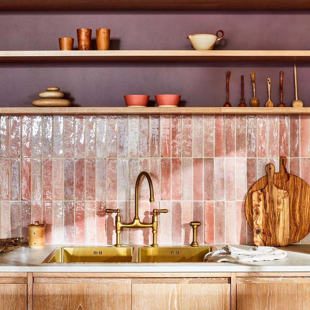Küchenumgebung mit glänzenden Elazar Rosa Ziegelfliesen im Format 6 × 25 cm, die sanfte Rosétöne und natürliche Farbnuancen zeigen, kombiniert mit warmen Holzschränken, offenen Regalen und Messingarmaturen für ein entspanntes, designorientiertes Gesamtbild.