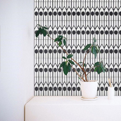 Innenwand mit Almeira Felis Fliesen im marokkanischen Stil im Format 20 × 20 cm für Wand und Boden, gestaltet als markante schwarz-weiße geometrische Akzentwand. Kombiniert mit minimalistischen Möbeln und grünen Topfpflanzen für eine moderne, klare Raumwirkung.