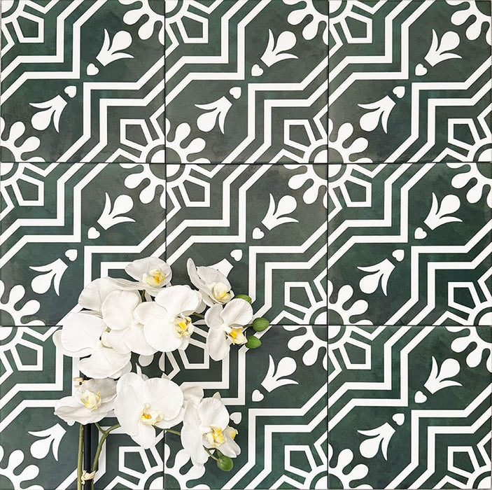 Flatlay mit Berlin Grün Fliesen im Format 20 × 20 cm im viktorianisch inspirierten Stil in Grün und Weiß. Kräftige geometrische und florale Motive werden mit weißen Orchideen kombiniert, um Kontrast und eine dekorative Wirkung zu erzeugen.