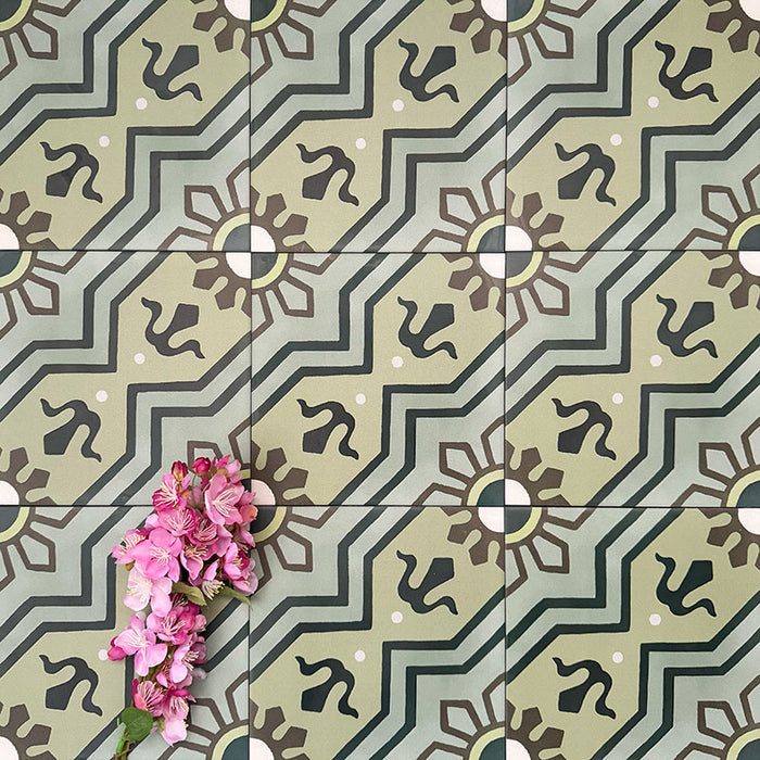 Detailaufnahme von Berlin Nikolai Feinsteinzeugfliesen im Format 20 × 20 cm im marokkanisch inspirierten Stil, verlegt in einem wiederkehrenden Muster. Hervorgehoben wird das geometrische Design in abgestuften Grüntönen mit dunklen Akzenten, ergänzt durch rosa Blumen, die die feinen Details und die matte Oberfläche betonen.
