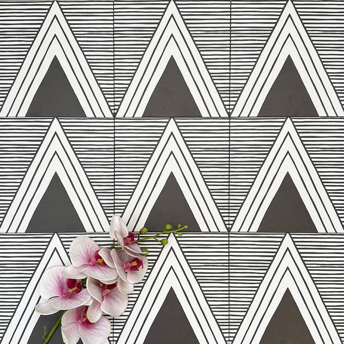 Almeira Giza Feinsteinzeugfliesen im marokkanischen Stil für Wand und Boden, angeordnet in einem sich wiederholenden geometrischen Dreiecksmuster in Schwarz und Weiß, Format 20 × 20 cm, mit dekorativen Blumen in Szene gesetzt.