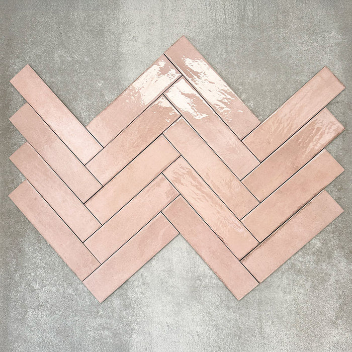 Nomadin Rose Ziegel-Wandfliesen im Format 6 × 24,6 cm, im Fischgrätmuster verlegt, um den sanften Roséton, die glänzende Oberfläche und die feine Oberflächenvariation hervorzuheben.