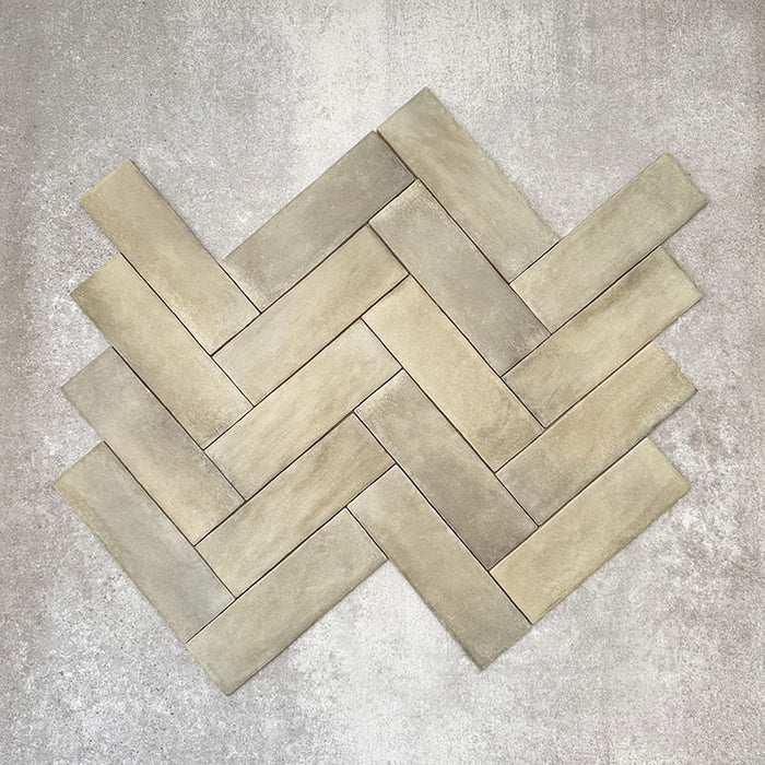 Flatlay von Zellige Waldgrün Matt Keramik-Riemchenfliesen im marokkanischen Stil im Format 6,5 × 20 cm, im Fischgrätmuster gezeigt. Sanfte Grün- und Erdtöne, leicht unregelmäßige Kanten und die handwerkliche Glasuroptik werden vor neutralem Hintergrund hervorgehoben.