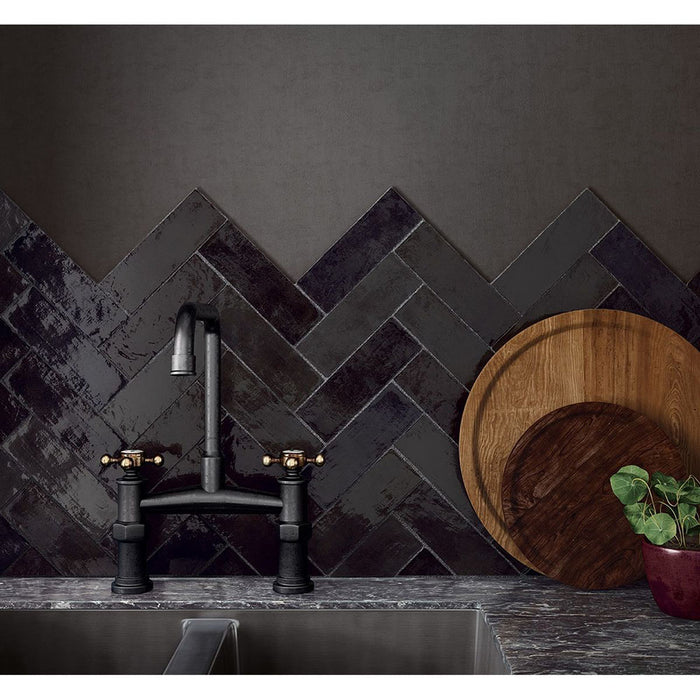 Schwarze Zellige-Ziegelfliesen im marokkanischen Stil, im Fischgrätmuster verlegt und als Küchenrückwand gezeigt. Kombiniert mit einer dunklen Steinarbeitsplatte, schwarzer Armatur und warmen Holzaccessoires entsteht ein ausdrucksstarker Kontrast.