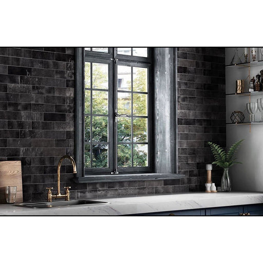 Schwarze Zellige-Ziegelfliesen im marokkanischen Stil, im Fischgrätmuster verlegt und als Küchenrückwand gezeigt. Kombiniert mit einer dunklen Steinarbeitsplatte, schwarzer Armatur und warmen Holzaccessoires entsteht ein ausdrucksstarker Kontrast.