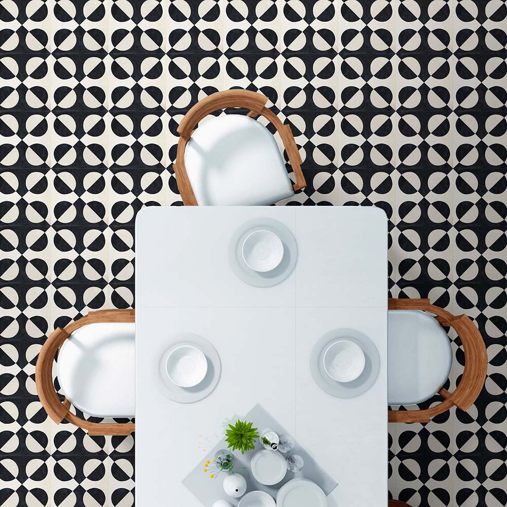 Essbereich, gestaltet mit  Abstrakte Schwarze Illusion Musterfliese im Format 20 × 20 cm, verlegt als markantes geometrisches Bodendesign. Das kontrastreiche Kreis­muster in Schwarz und sanftem Creme erzeugt einen eindrucksvollen Effekt optischer Illusion und wird mit einem weißen Esstisch und Holzstühlen kombiniert – für ein klares, modernes Interieur.