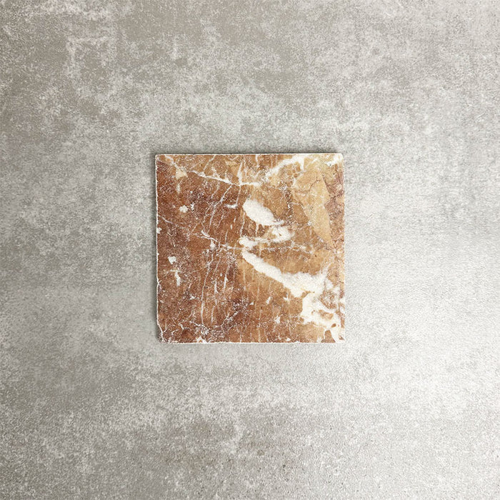 Einzelne Fayrouz Rosso 15,2 × 15,2 cm Naturmarmorfliese mit getrommelter Oberfläche in warmen Rottönen mit markanter natürlicher Maserung, präsentiert vor einem neutralen, strukturierten Hintergrund in einer klaren Produktszene.