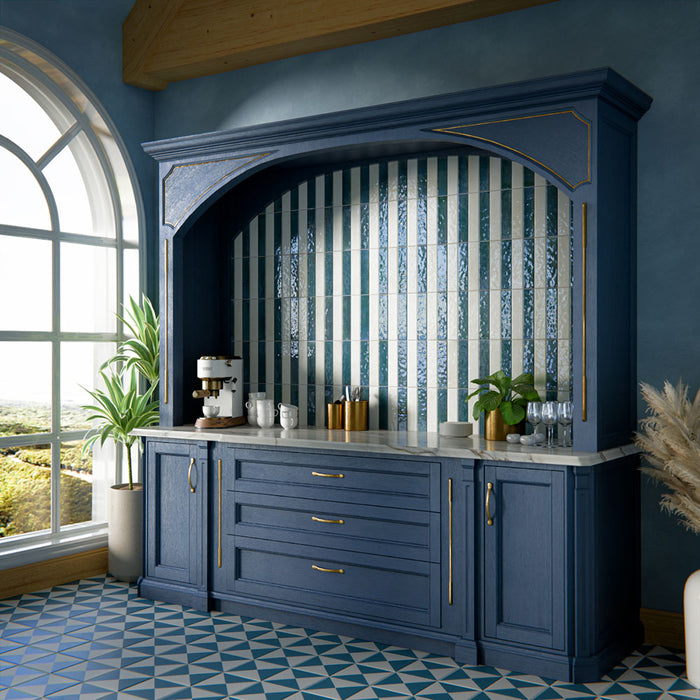Kitchen interior featuring Allegra Blanca 6x25cm gloss brick tiles, installed vertically within a statement alcove, showcasing soft white tones with a reflective glazed finish, styled with deep blue cabinetry, brass accents, and a marble-effect worktop for a refined, elegant contrast.