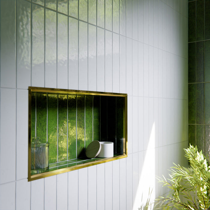 Modernes Badezimmer mit Bora Bora Ziegel Weißer Sand Keramik-Wandfliesen im schlanken Riemchenformat 6,5 × 32,8 cm mit Fluxglasur, vertikal und horizontal verlegt, um eine weich strukturierte Akzentwand zu schaffen. In Kombination mit freistehender Badewanne, Messingarmaturen, natürlichem Licht und Pflanzen entsteht eine ruhige, spaähnliche Atmosphäre.