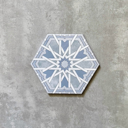 Einzelne sechseckige Porzellanfliese Medina Hormuz Azurblau im marokkanischen Stil (18,7 × 21,6 cm) mit einem ausdrucksstarken, sterninspirierten geometrischen Muster in sanften Blau- und Weißtönen, gezeigt vor neutralem Hintergrund.