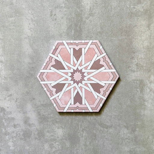 Einzelne Medina Hormuz Rosa sechseckige Porzellanfliese im marokkanischen Stil (18,7 × 21,6 cm) mit einem markanten, sterninspirierten geometrischen Muster in soften Rosé- und Weißtönen, auf neutralem Hintergrund dargestellt.