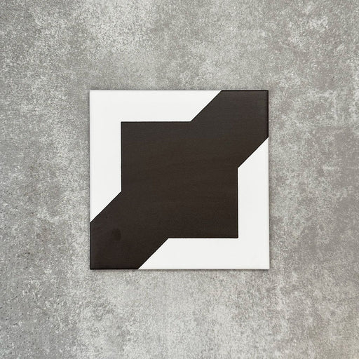 Einzelne Almeria Kathedrale Feinsteinzeugfliese im marokkanischen Stil im Format 20 × 20 cm mit einem kräftigen geometrischen Design in Schwarz und Weiß, geeignet für Wand- und Bodenflächen.