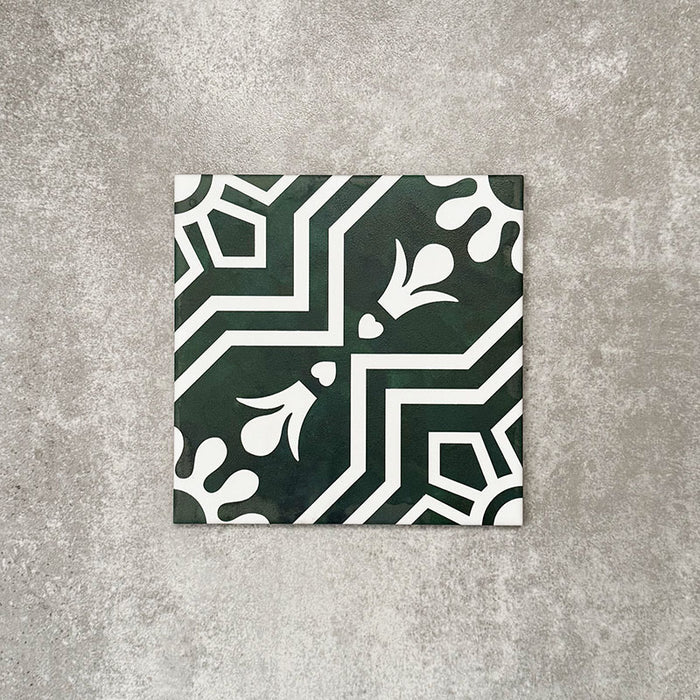 Einzelne Berlin Grün Keramikfliese im Format 20 × 20 cm im viktorianisch inspirierten Stil in Grün und Weiß mit markantem geometrischem und floralem Motiv, inspiriert von marokkanischem Design, präsentiert vor einem neutralen, strukturierten Hintergrund.
