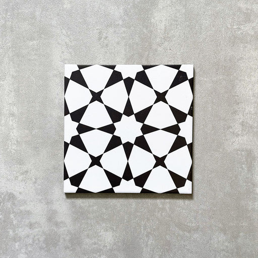Einzelne Agadir Schwarz & Weiß Fliese im marokkanischen Stil im Format 20 × 20 cm aus Feinsteinzeug mit einem markanten geometrischen Sternmuster in Schwarz und Weiß, dargestellt auf neutralem Hintergrund.