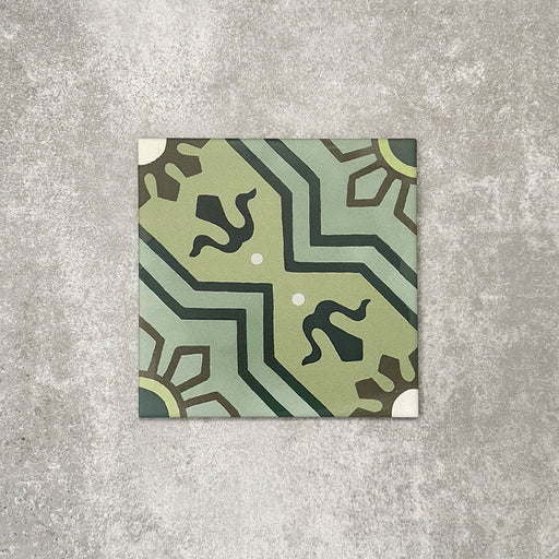 Einzelne Berlin Nikolai Feinsteinzeugfliese im Format 20 × 20 cm im marokkanisch inspirierten Stil vor einem neutralen Hintergrund in Steinoptik. Sichtbar ist ein detailreiches geometrisches Muster in abgestuften Grüntönen mit kontrastierenden dunklen Akzenten und matter Oberfläche im traditionell inspirierten Design.