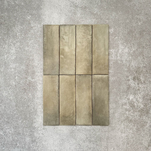 Flatlay von Zellige Waldgrün Matt Keramik-Riemchenfliesen im marokkanischen Stil im Format 6,5 × 20 cm, mit weichen grünen und erdigen Farbnuancen, leicht unregelmäßigen Kanten und handwerklicher Glasuroptik vor neutralem Hintergrund.