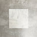 Vier Fayrouz White 15,2 × 15,2 cm Naturmarmorfliesen mit getrommelter Oberfläche nebeneinander angeordnet, die sanften Weißtöne, feine Maserung und natürliche Variation vor einem neutralen, strukturierten Hintergrund zeigen.
